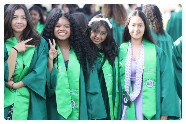 Four students dressed in green graduation robes.